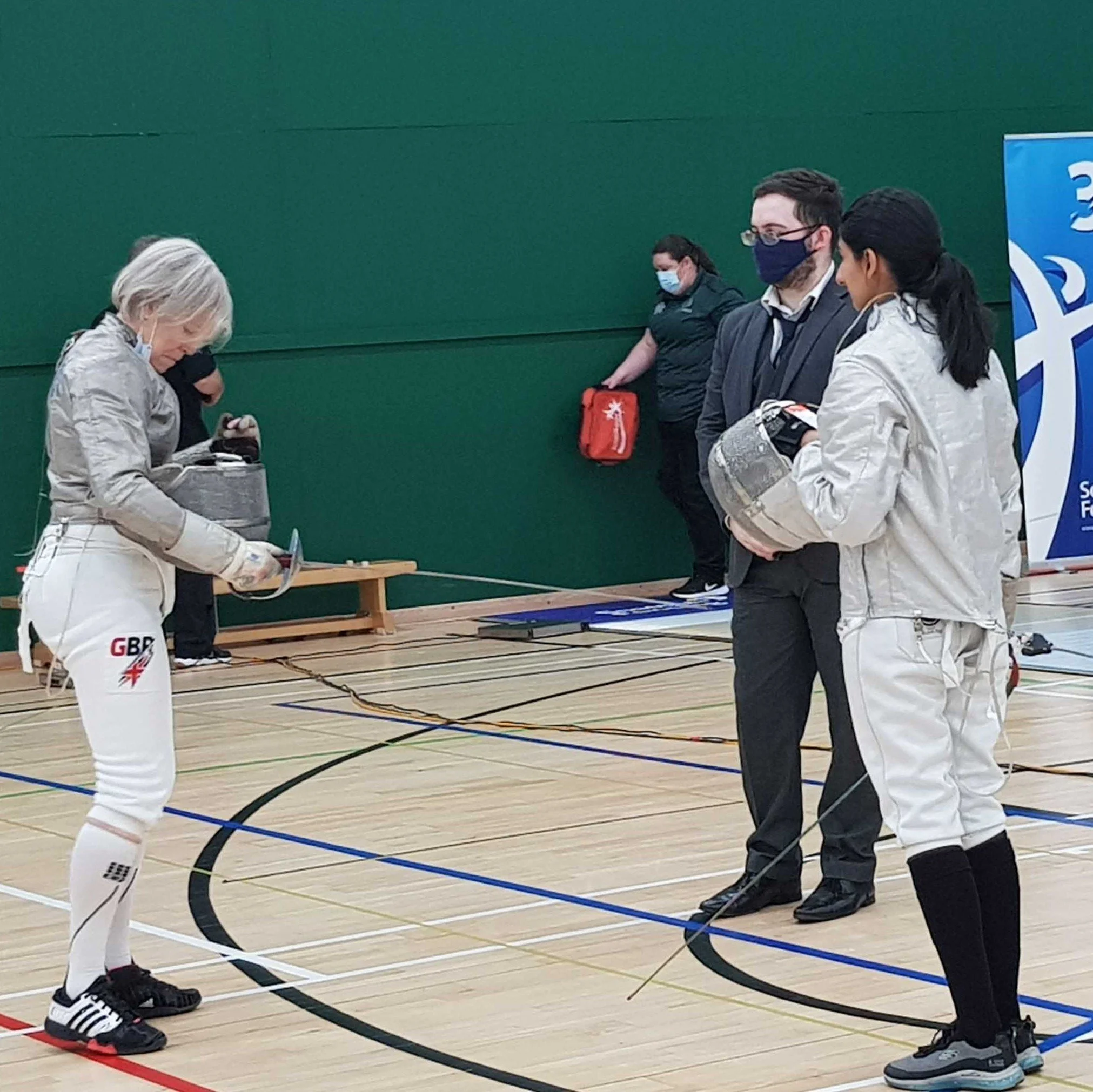 A women's sabre match about to begin with an older women about to fence a younger competitor